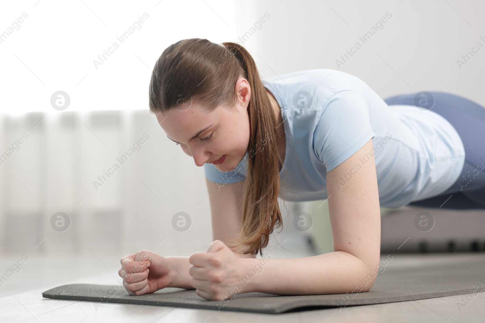 Woman in sportswear doing plank exercise at home Photo of Woman in sportswear doing plank exercise at home