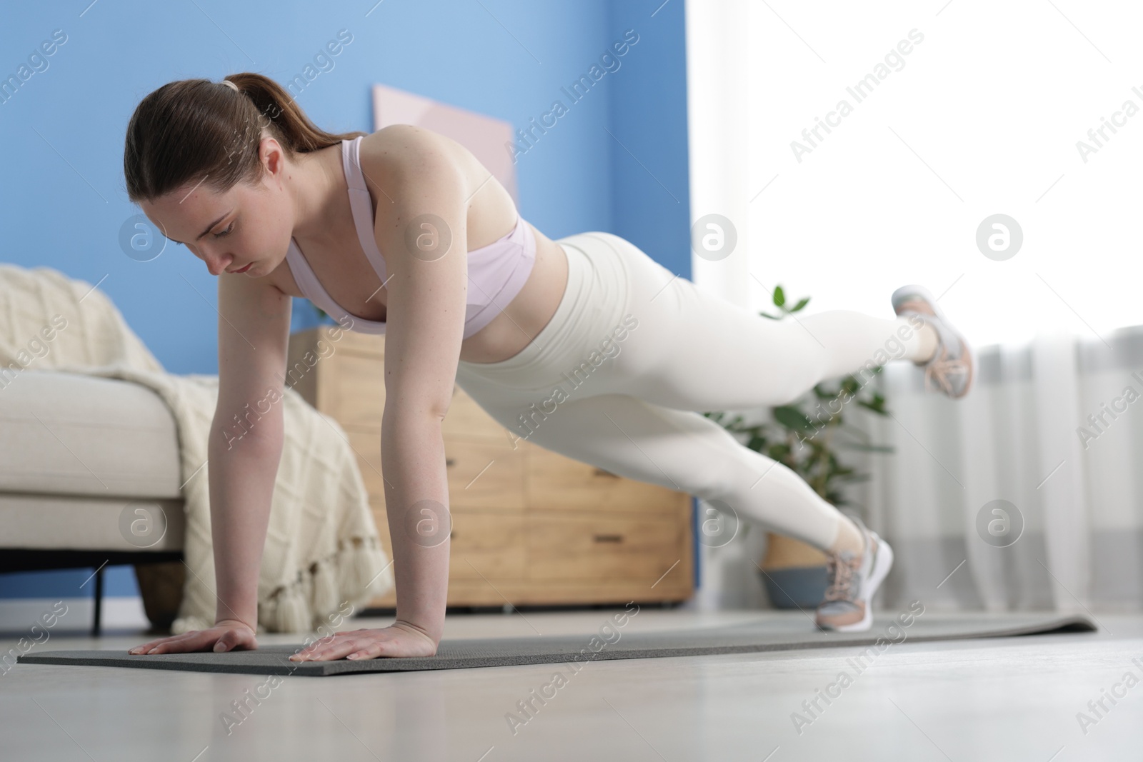 Woman in sportswear doing plank exercise at home Photo of Woman in sportswear doing plank exercise at home