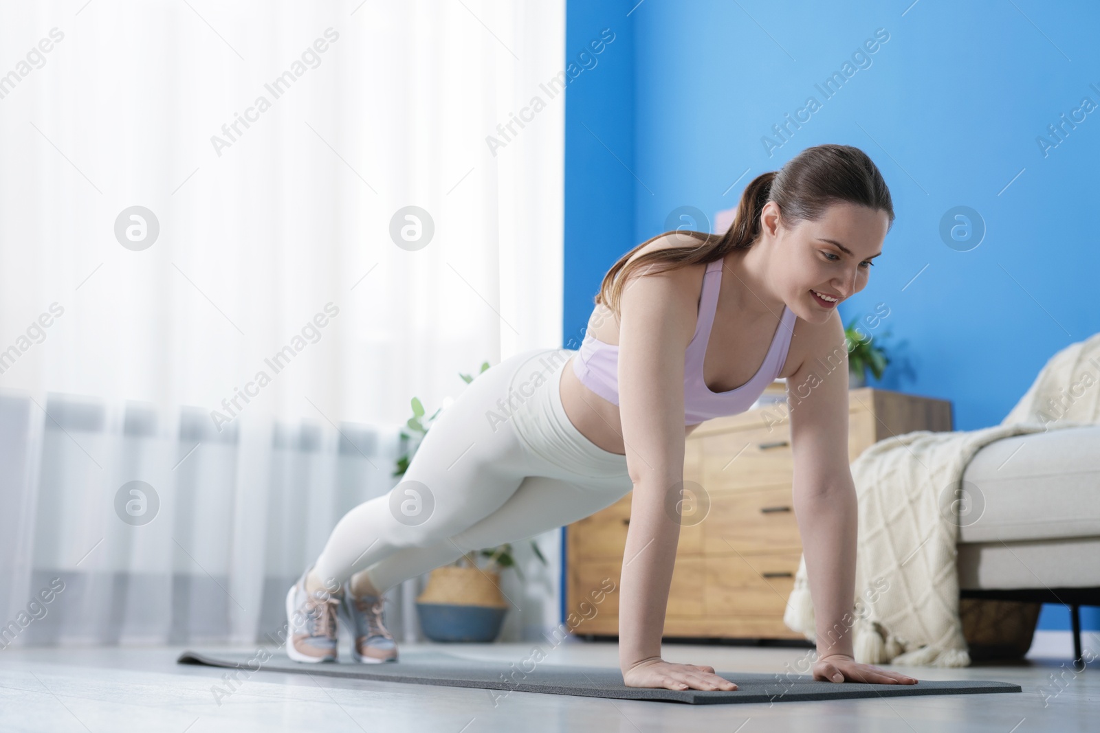 Woman in sportswear doing plank exercise at home Photo of Woman in sportswear doing plank exercise at home