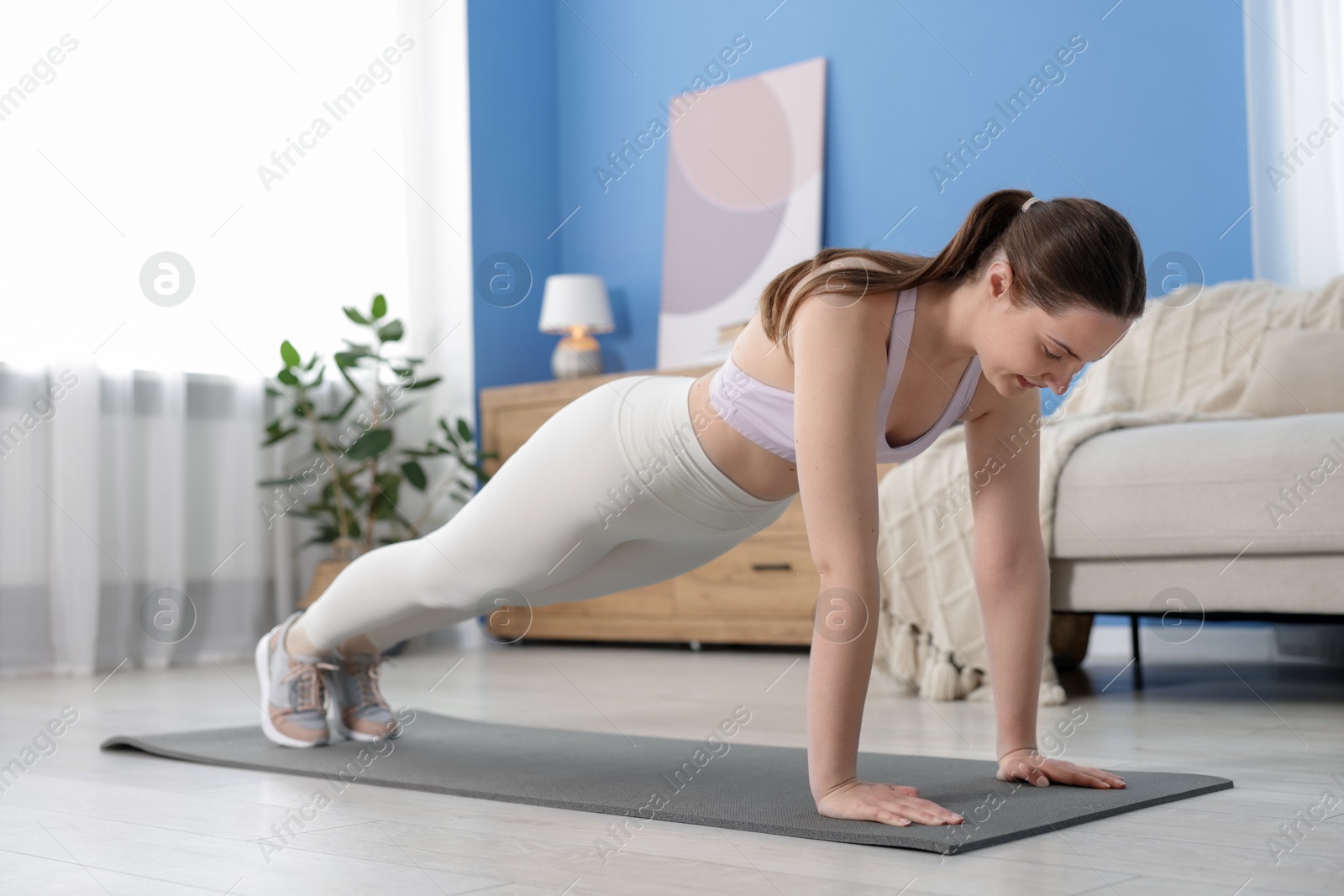 Woman in sportswear doing plank exercise at home Photo of Woman in sportswear doing plank exercise at home