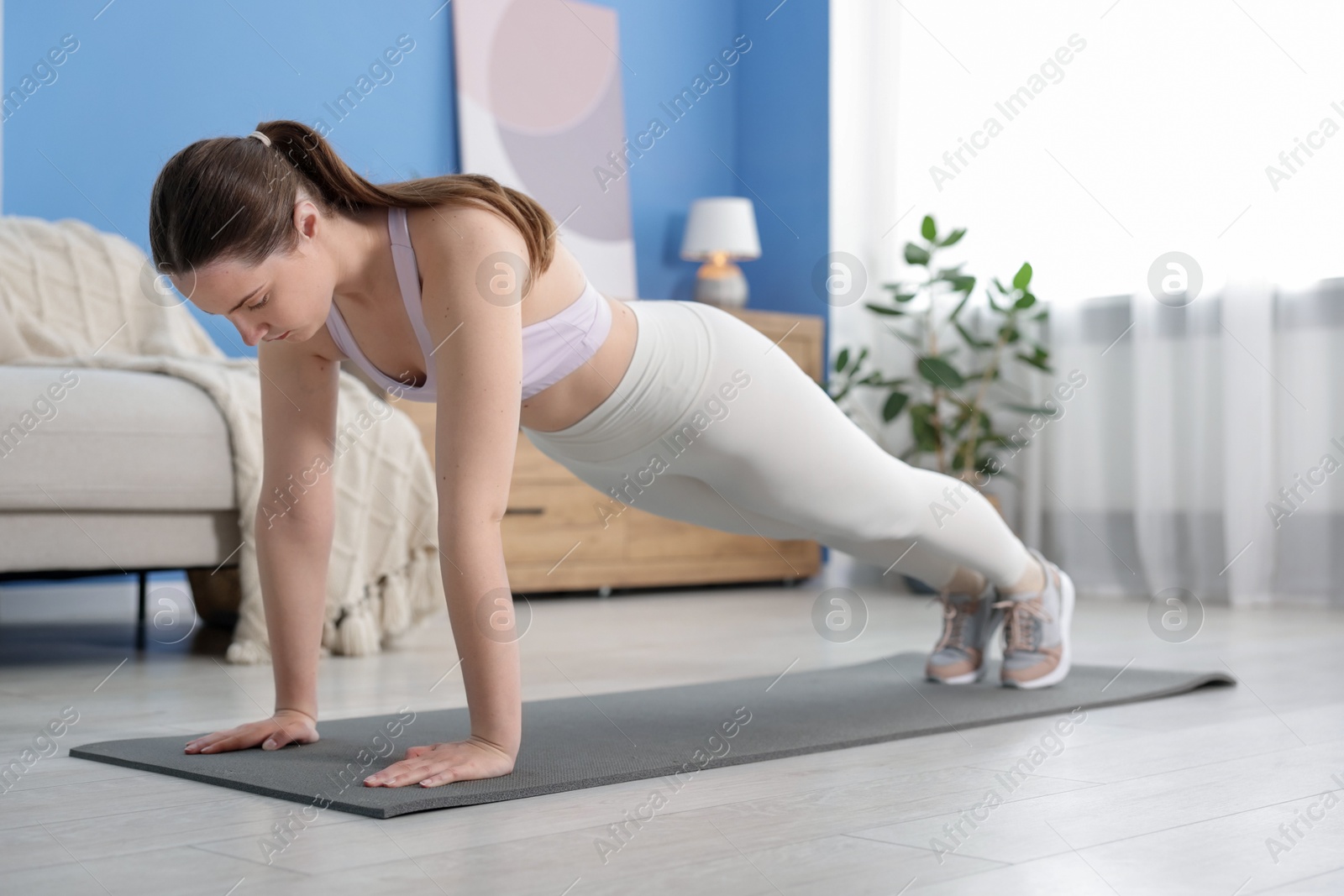 Woman in sportswear doing plank exercise at home Photo of Woman in sportswear doing plank exercise at home