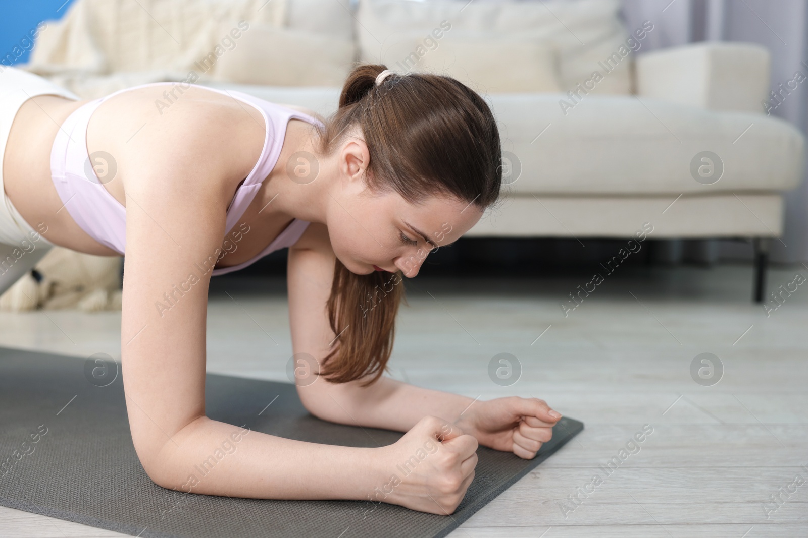 Woman in sportswear doing plank exercise at home, space for text Photo of Woman in sportswear doing plank exercise at home, space for text