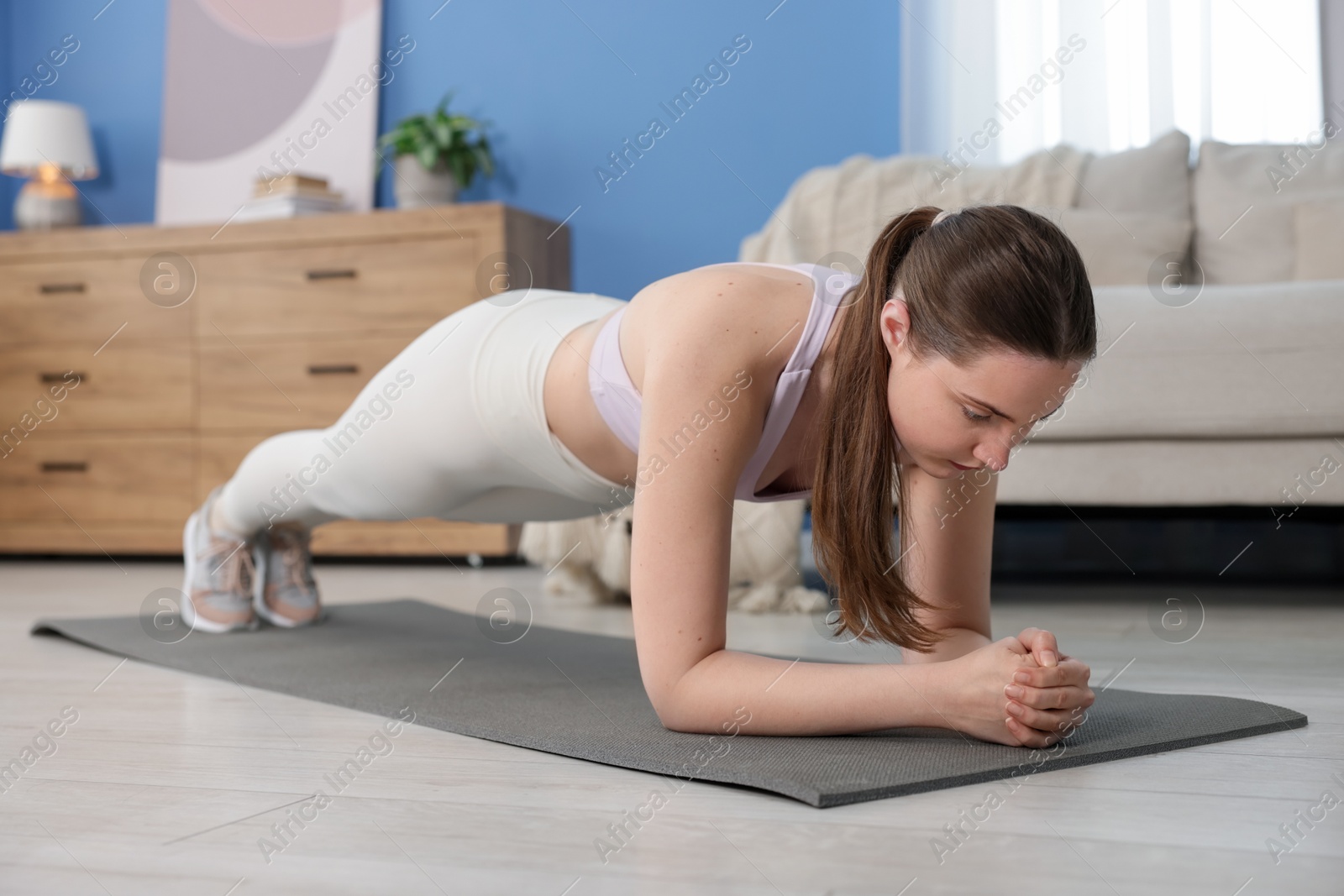 Woman in sportswear doing plank exercise at home Photo of Woman in sportswear doing plank exercise at home