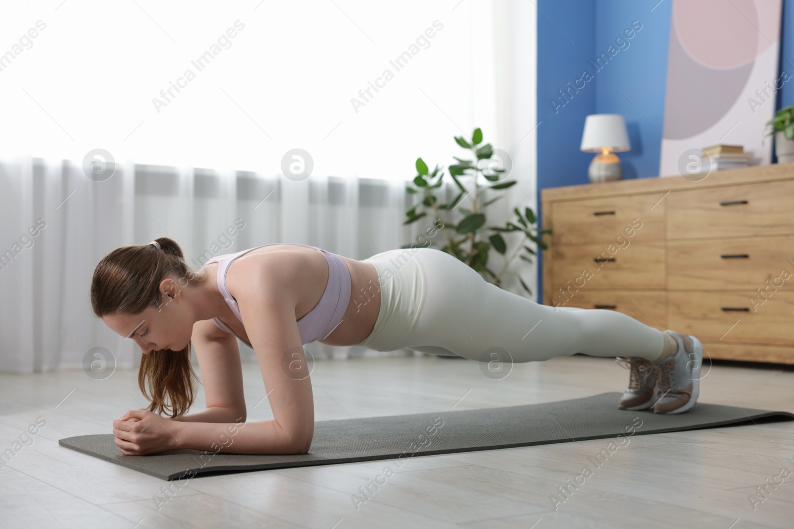 Woman in sportswear doing plank exercise at home Photo of Woman in sportswear doing plank exercise at home