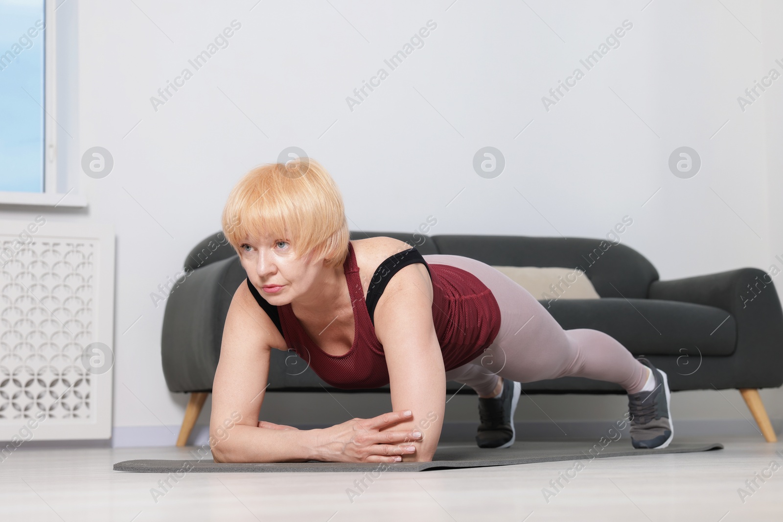 Senior woman in sportswear doing plank exercise at home Photo of Senior woman in sportswear doing plank exercise at home