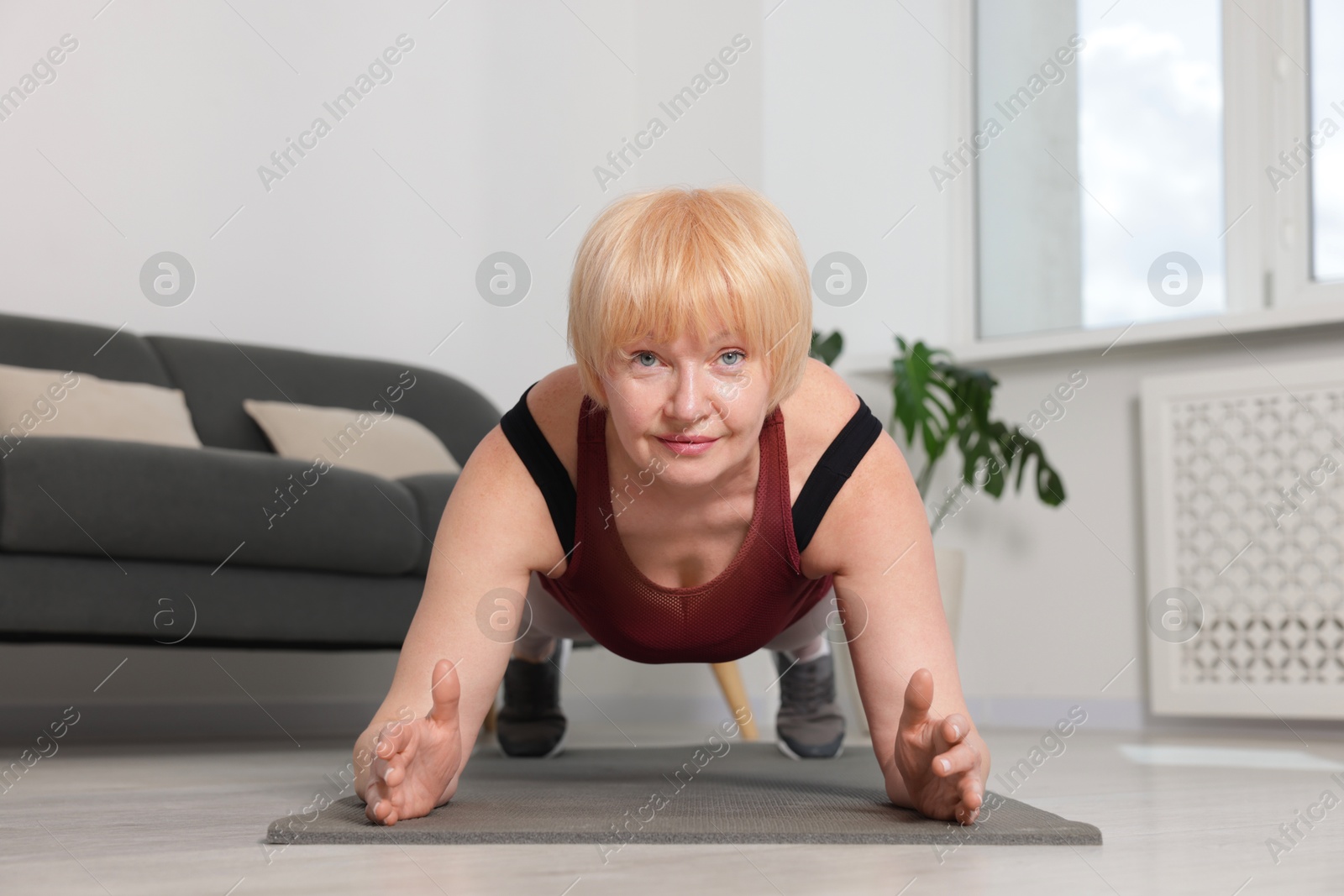Senior woman in sportswear doing plank exercise at home Photo of Senior woman in sportswear doing plank exercise at home