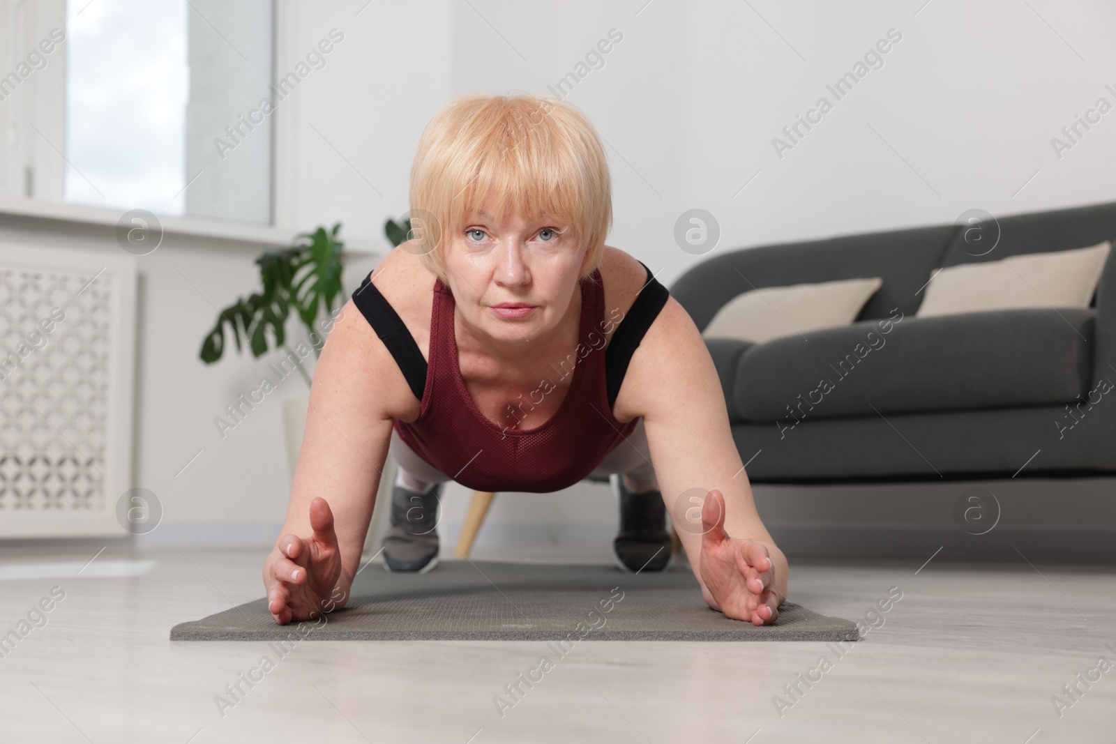Senior woman in sportswear doing plank exercise at home Photo of Senior woman in sportswear doing plank exercise at home