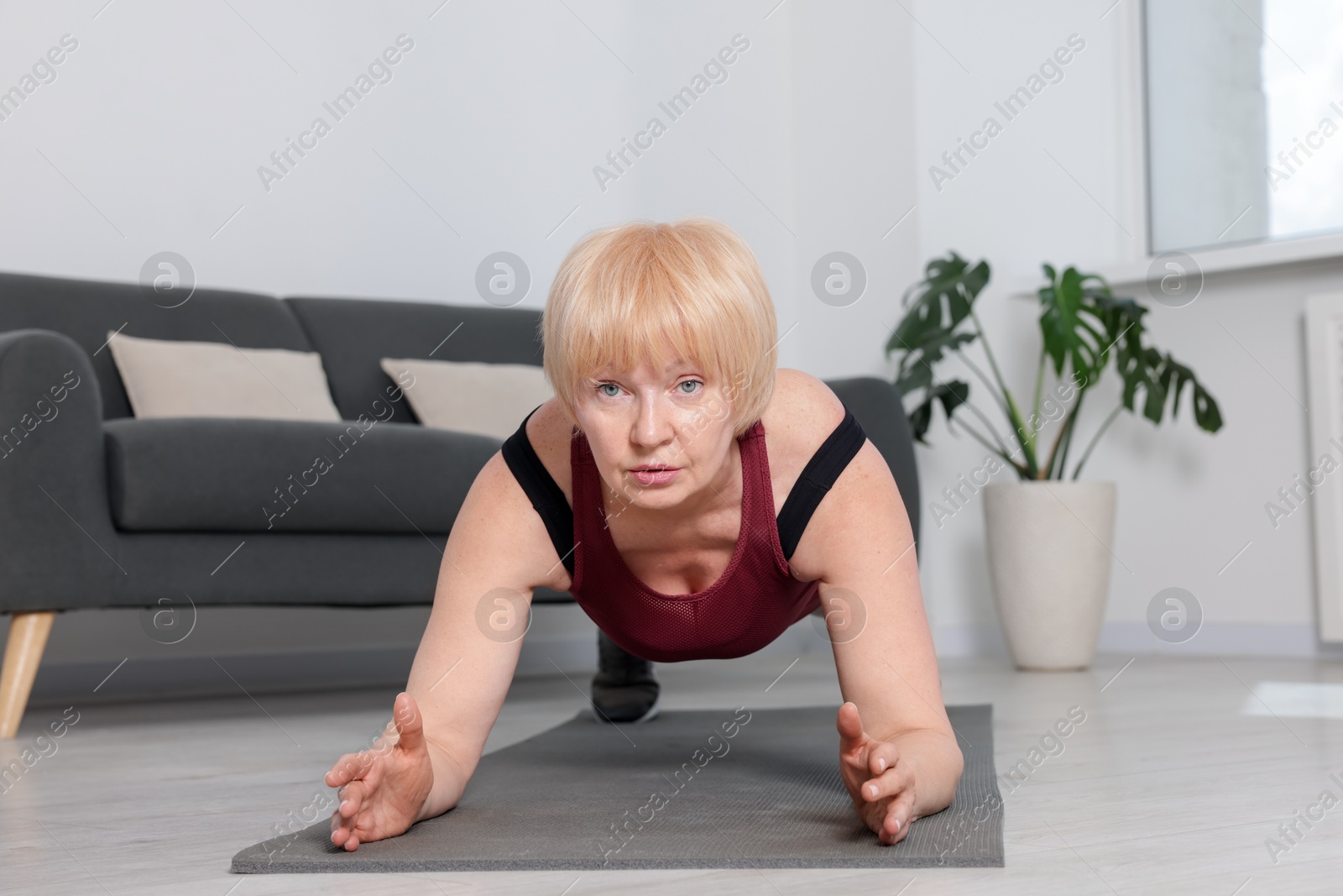 Senior woman in sportswear doing plank exercise at home Photo of Senior woman in sportswear doing plank exercise at home