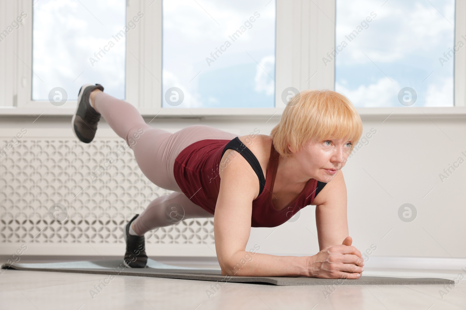 Senior woman in sportswear doing plank exercise at home Photo of Senior woman in sportswear doing plank exercise at home