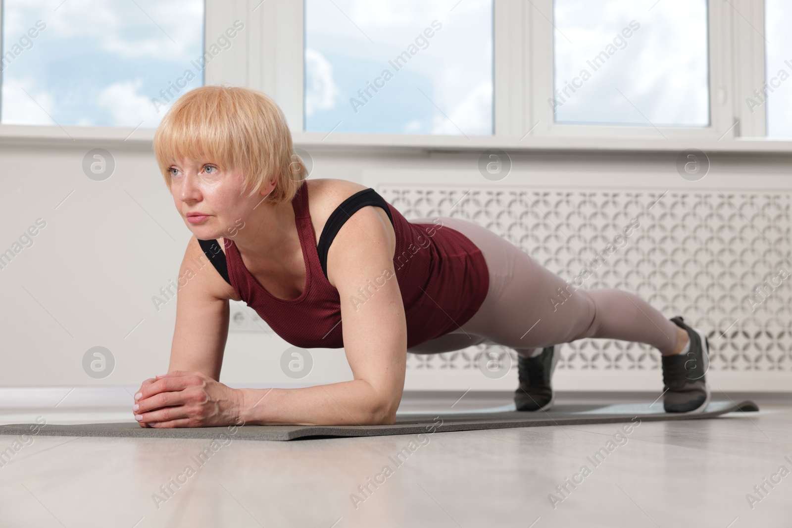 Senior woman in sportswear doing plank exercise at home Photo of Senior woman in sportswear doing plank exercise at home