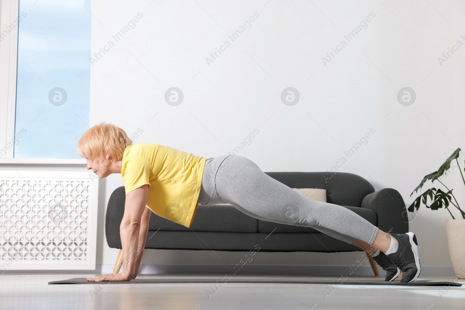 Senior woman in sportswear doing plank exercise at home Photo of Senior woman in sportswear doing plank exercise at home