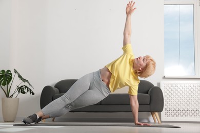 Photo of Senior woman in sportswear doing plank exercise at home