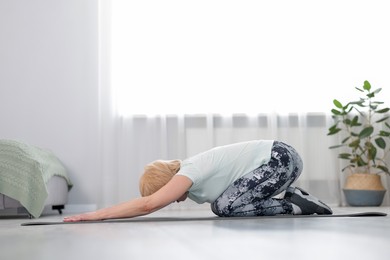 Photo of Senior woman in sportswear doing exercise at home
