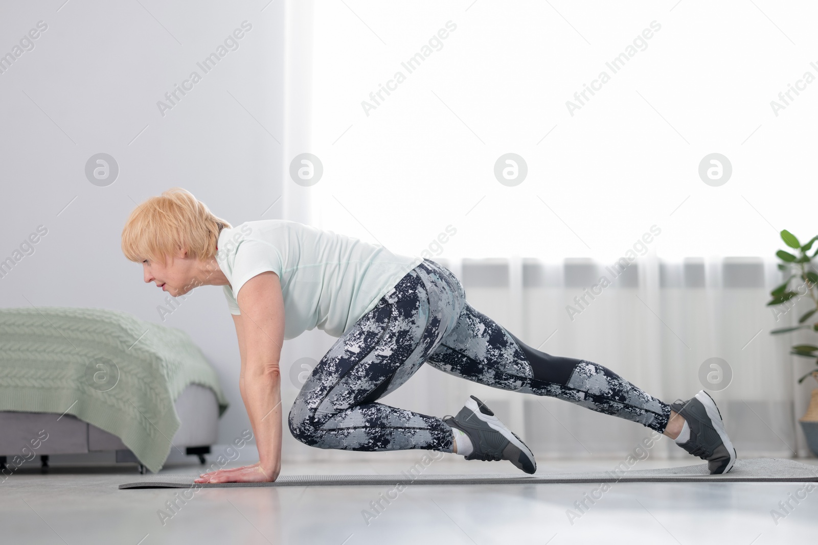 Senior woman in sportswear doing plank exercise at home Photo of Senior woman in sportswear doing plank exercise at home