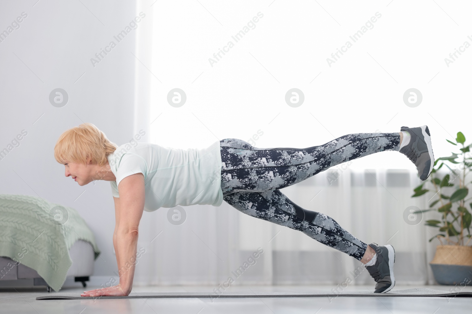 Senior woman in sportswear doing plank exercise at home Photo of Senior woman in sportswear doing plank exercise at home