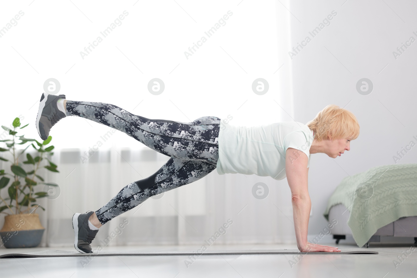 Senior woman in sportswear doing plank exercise at home Photo of Senior woman in sportswear doing plank exercise at home