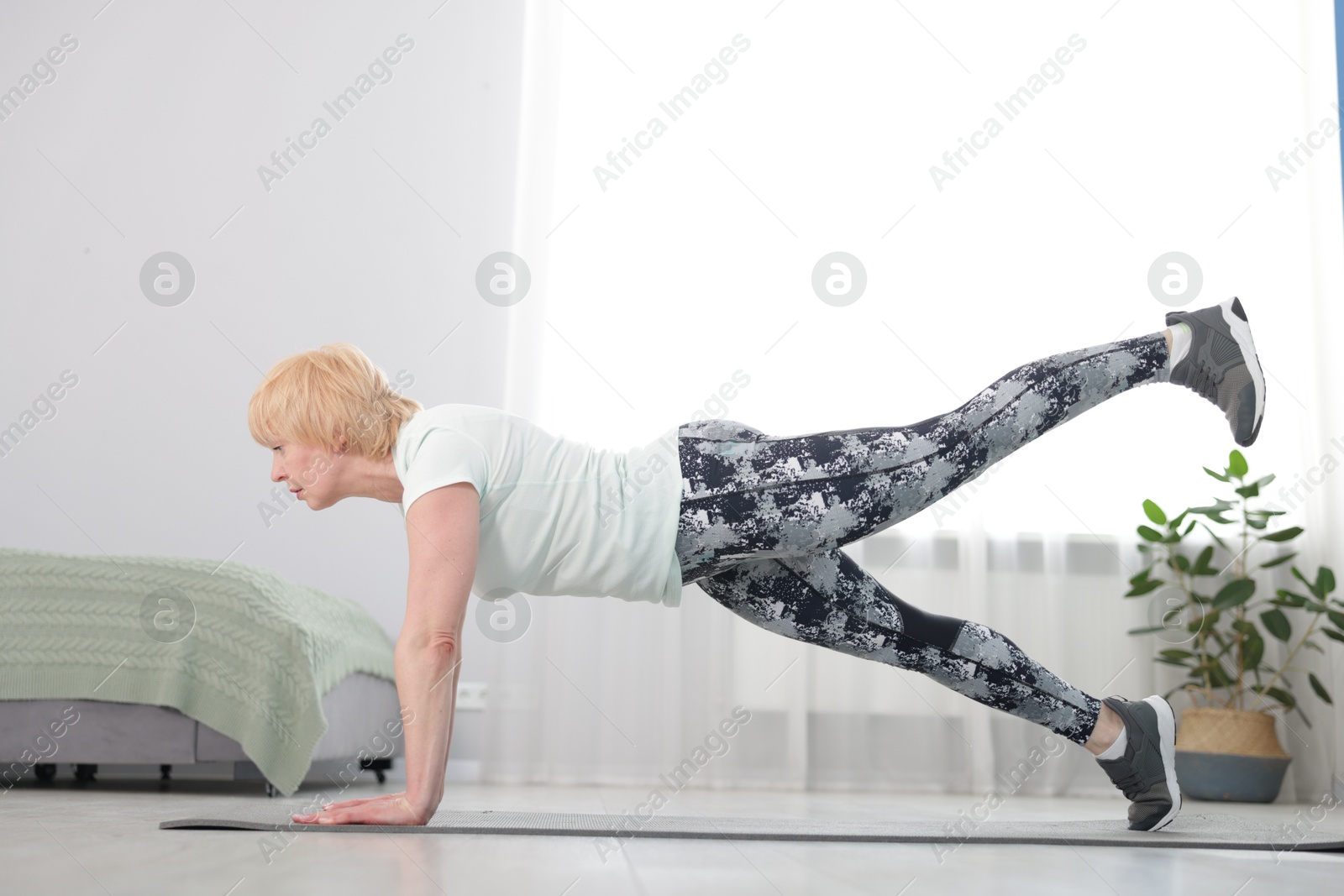 Senior woman in sportswear doing plank exercise at home Photo of Senior woman in sportswear doing plank exercise at home