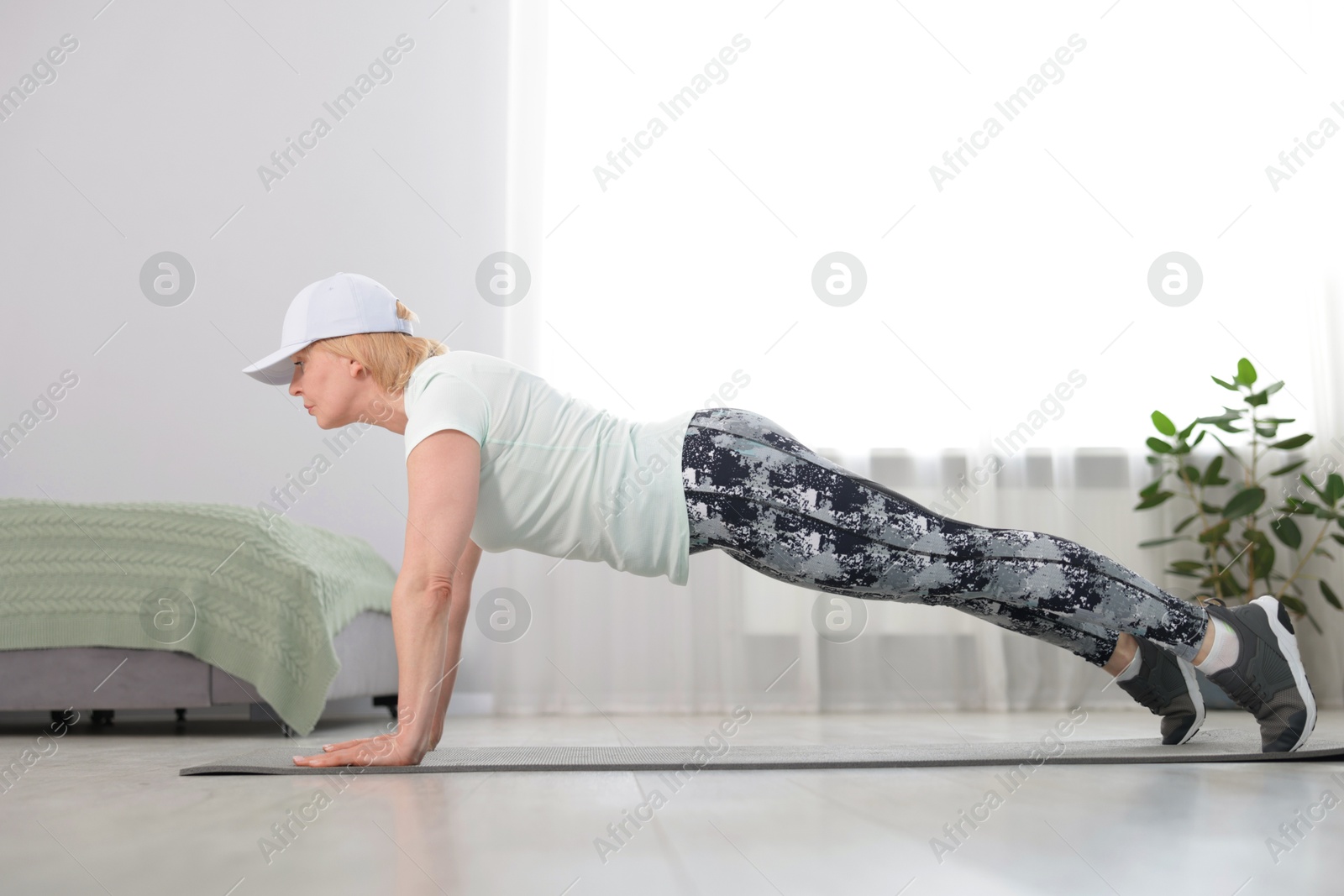 Senior woman in sportswear doing plank exercise at home Photo of Senior woman in sportswear doing plank exercise at home