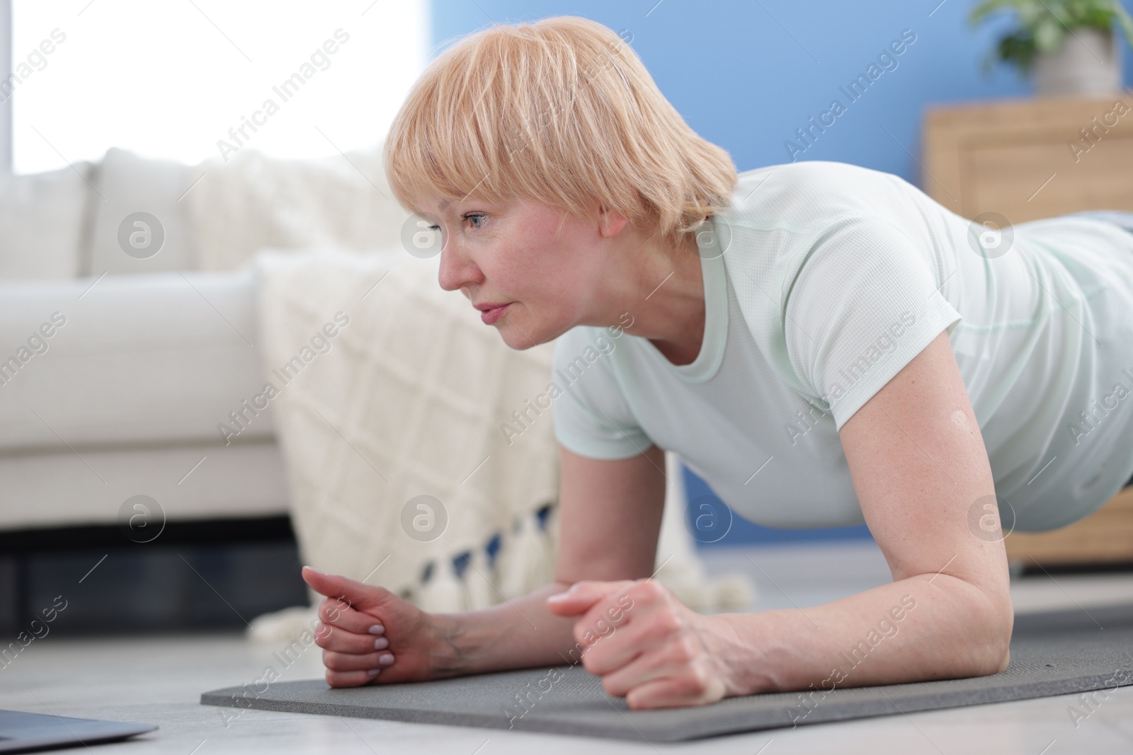 Senior woman in sportswear doing plank exercise at home, space for text Photo of Senior woman in sportswear doing plank exercise at home, space for text