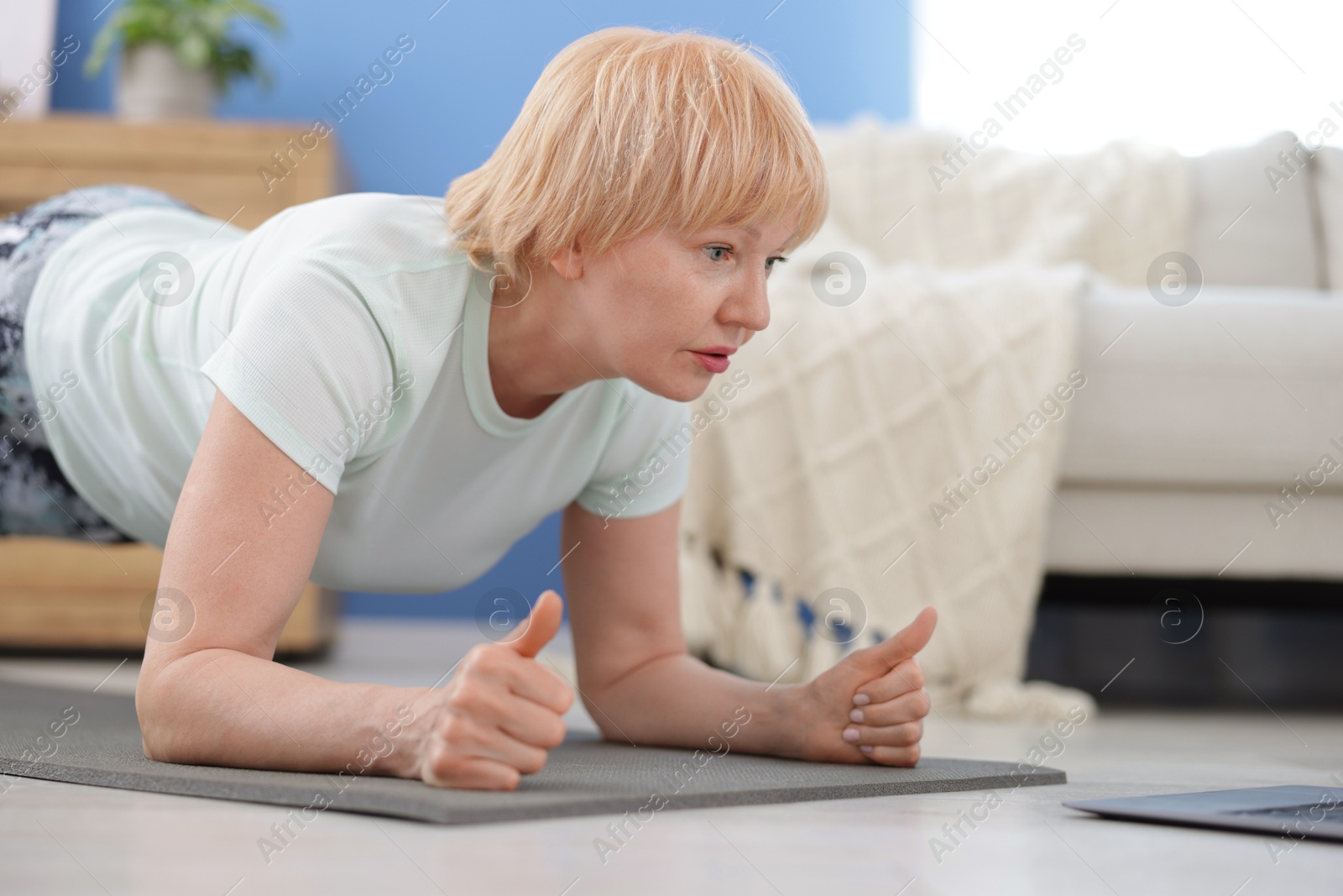 Senior woman in sportswear doing plank exercise at home, space for text Photo of Senior woman in sportswear doing plank exercise at home, space for text