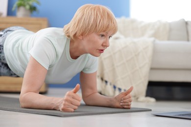 Photo of Senior woman in sportswear doing plank exercise at home, space for text