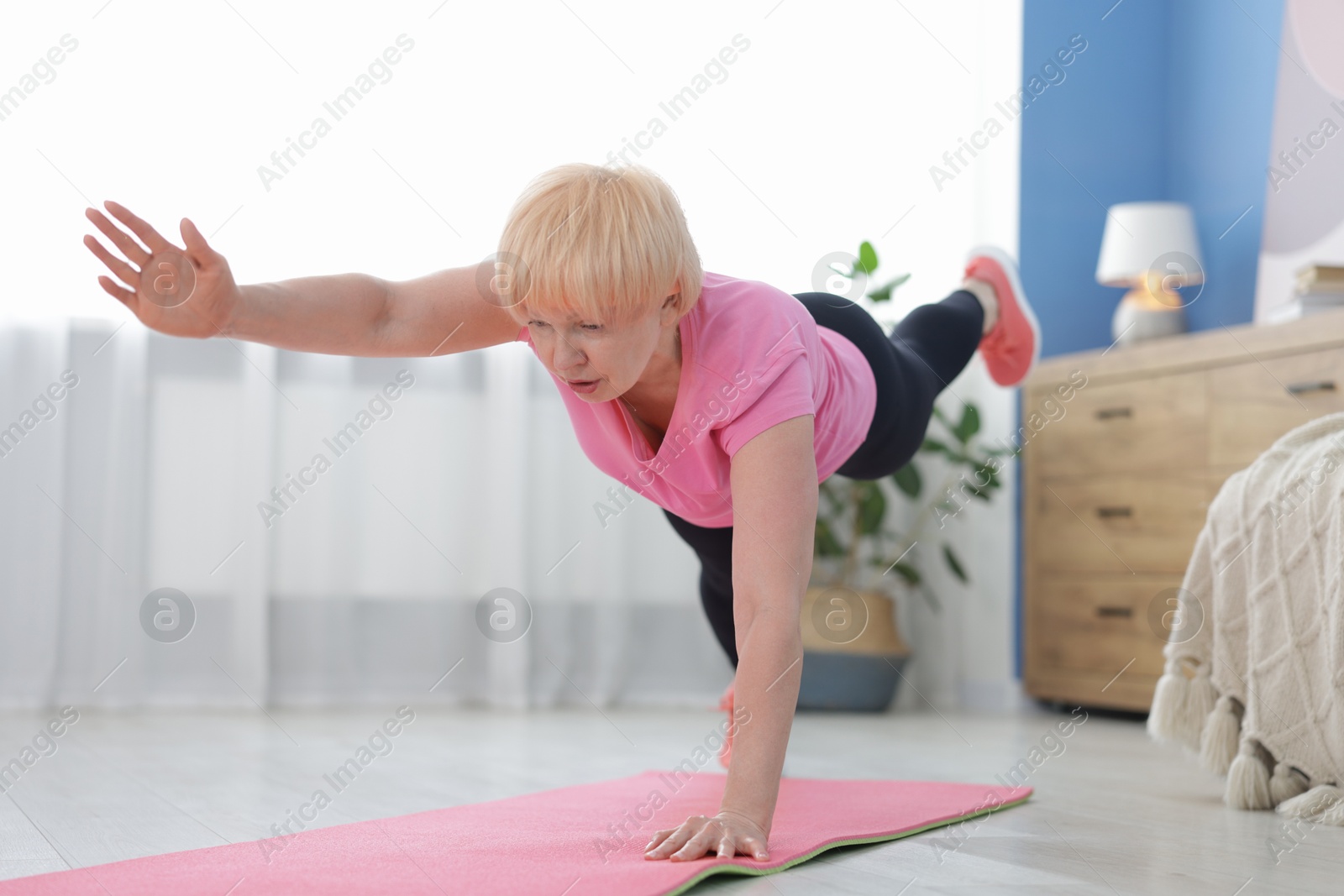 Photo of Senior woman in sportswear doing plank exercise at home