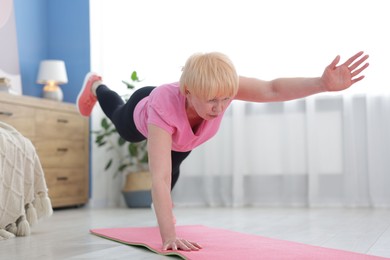 Photo of Senior woman in sportswear doing plank exercise at home