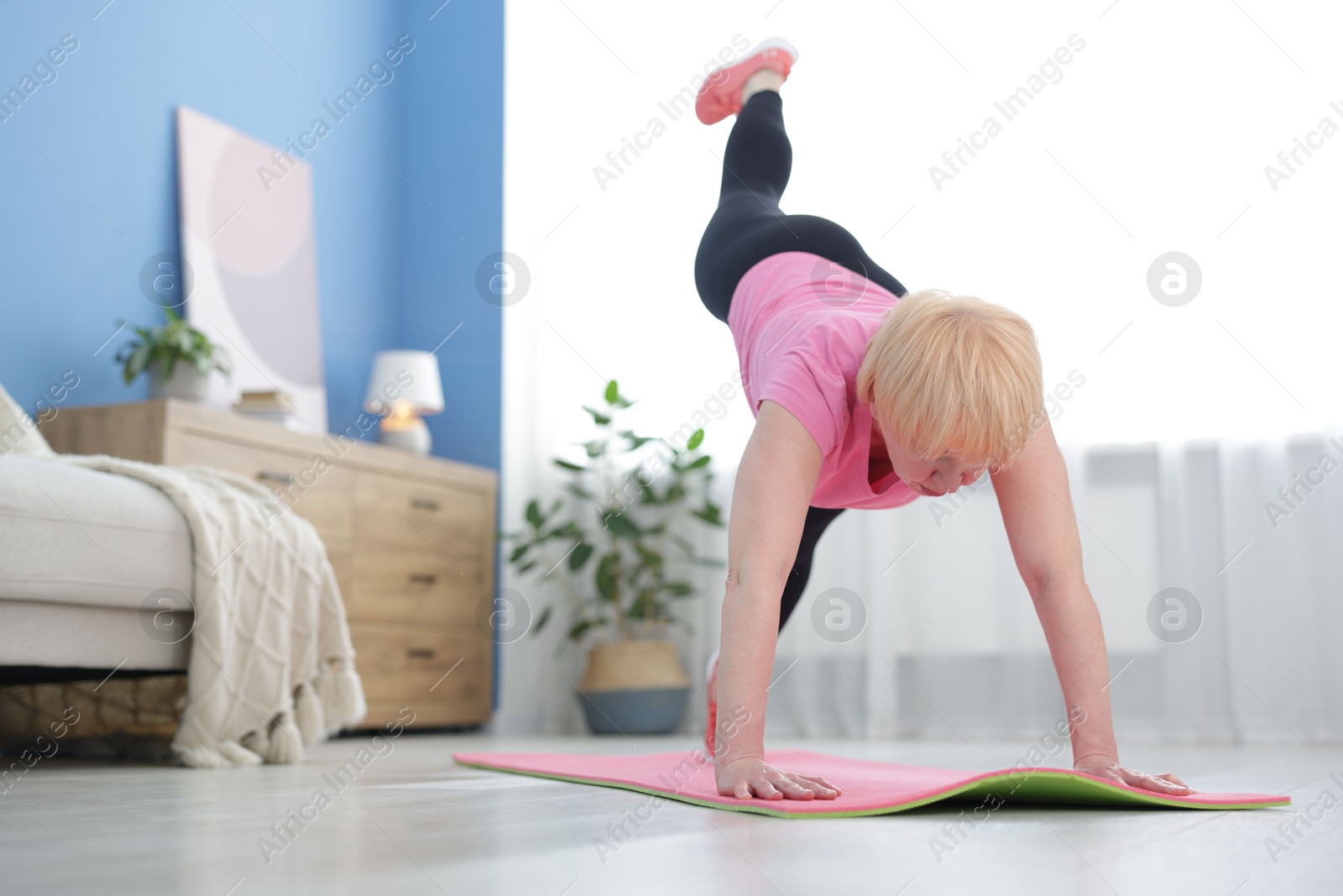 Photo of Senior woman in sportswear doing plank exercise at home, space for text