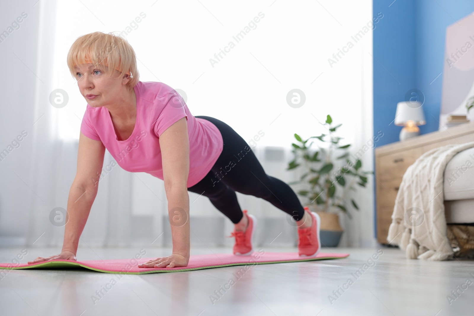 Photo of Senior woman in sportswear doing plank exercise at home, space for text