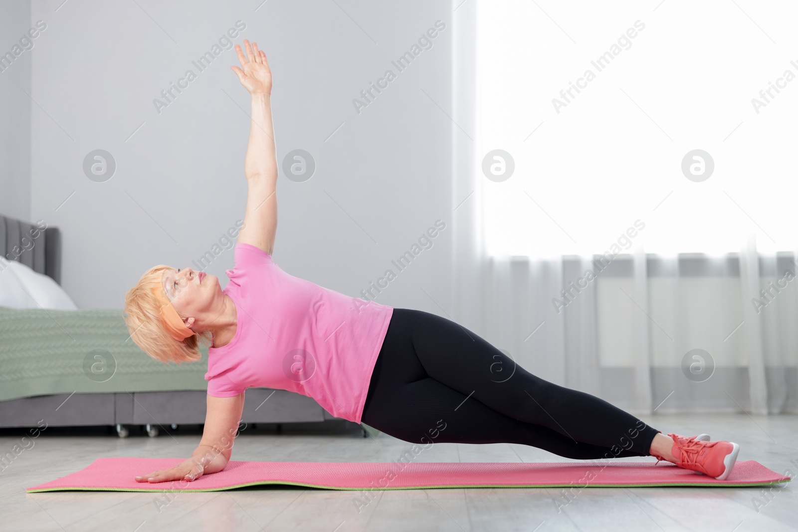 Photo of Senior woman in sportswear doing plank exercise at home