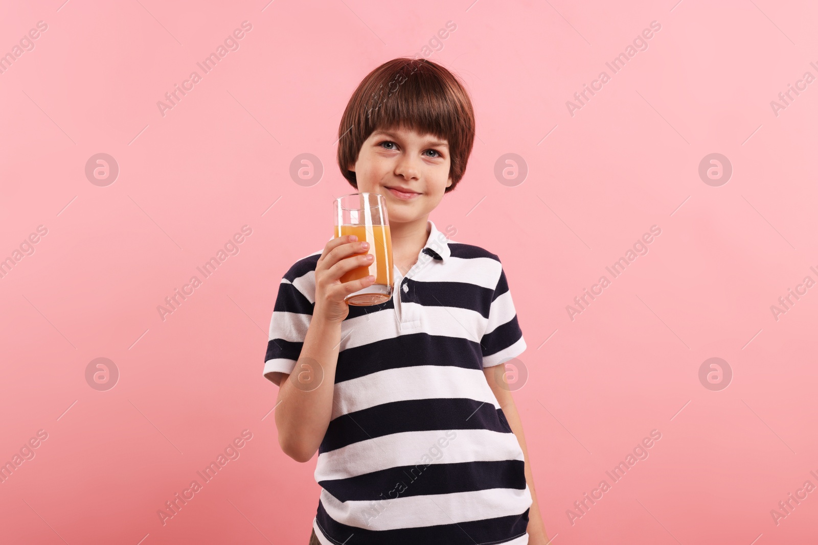 Cute little boy with glass of orange juice on pink background. Refreshing drink Photo of Cute little boy with glass of orange juice on pink background. Refreshing drink