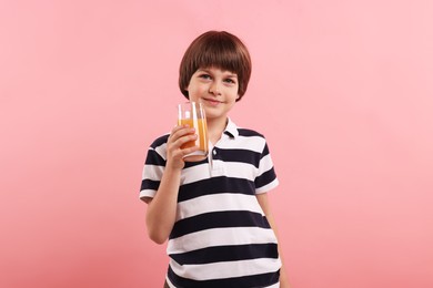 Photo of Cute little boy with glass of orange juice on pink background. Refreshing drink