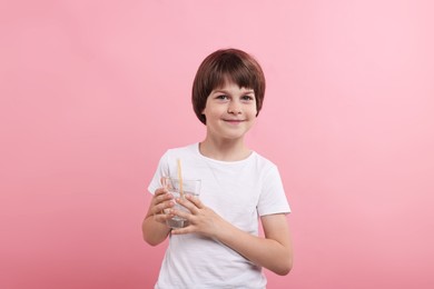 Photo of Cute little boy with glass of refreshing soda drink on pink background