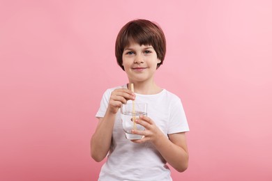 Photo of Cute little boy with glass of refreshing soda drink on pink background