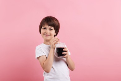 Photo of Cute little boy with glass of refreshing soda drink on pink background