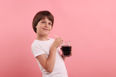 Photo of Cute little boy with glass of refreshing soda drink on pink background