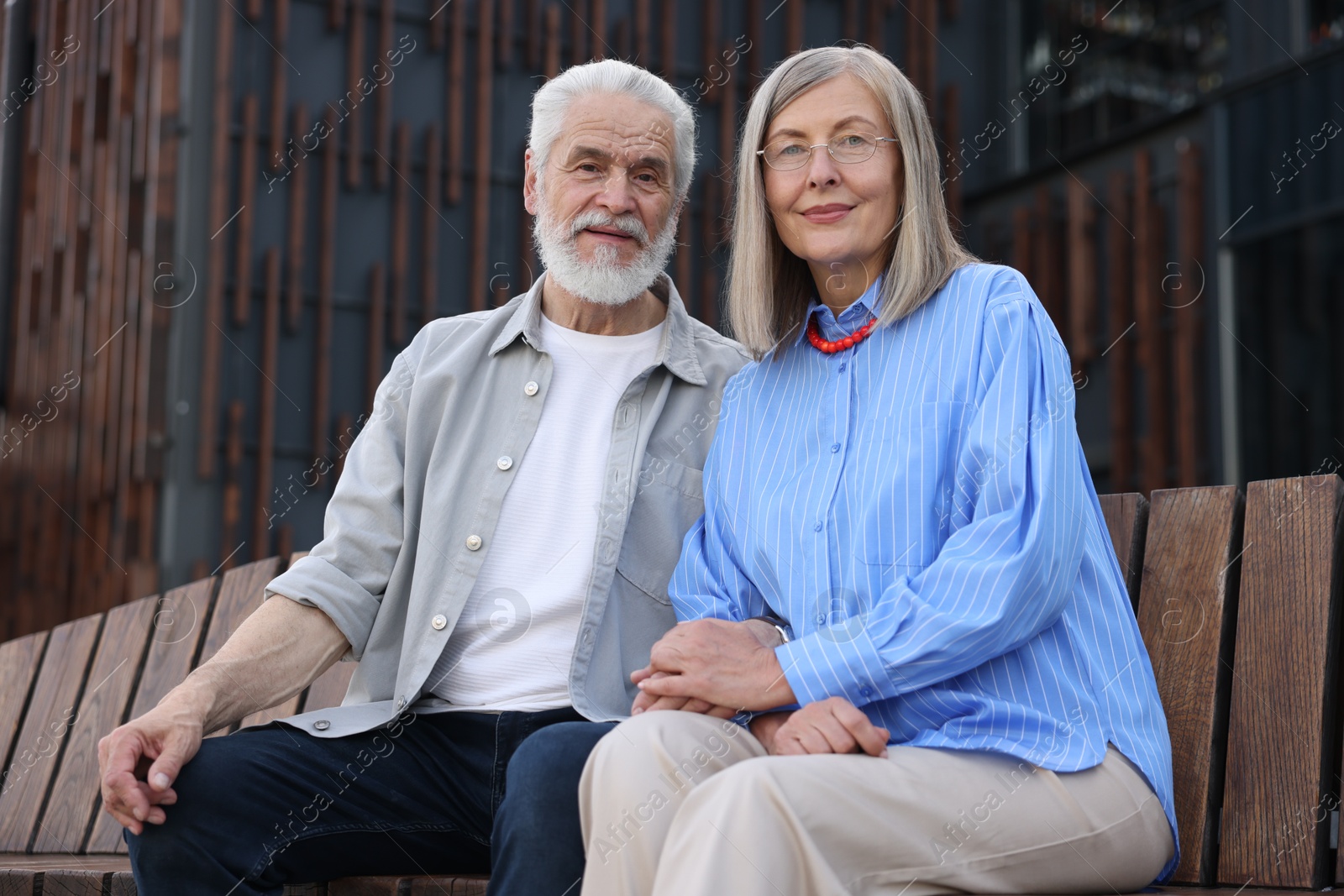 Lovely senior couple on bench near building outdoors Photo of Lovely senior couple on bench near building outdoors