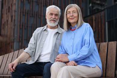 Photo of Lovely senior couple on bench near building outdoors