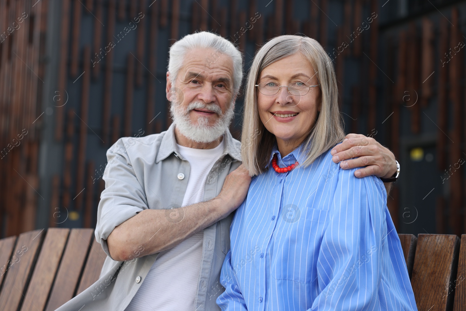 Lovely senior couple on bench near building outdoors Photo of Lovely senior couple on bench near building outdoors