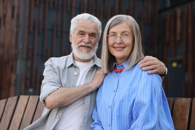 Photo of Lovely senior couple on bench near building outdoors