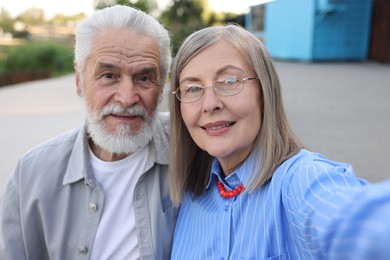 Photo of Lovely senior couple taking selfie in park