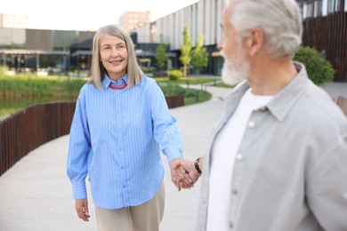 Photo of Lovely senior couple walking together on city street