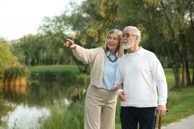 Photo of Lovely senior couple walking together near lake in park