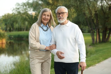 Photo of Lovely senior couple walking together near lake in park