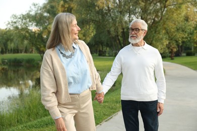 Photo of Lovely senior couple walking together near lake in park