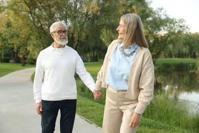 Photo of Lovely senior couple walking together near lake in park