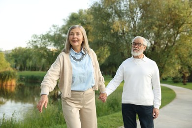 Photo of Lovely senior couple walking together near lake in park