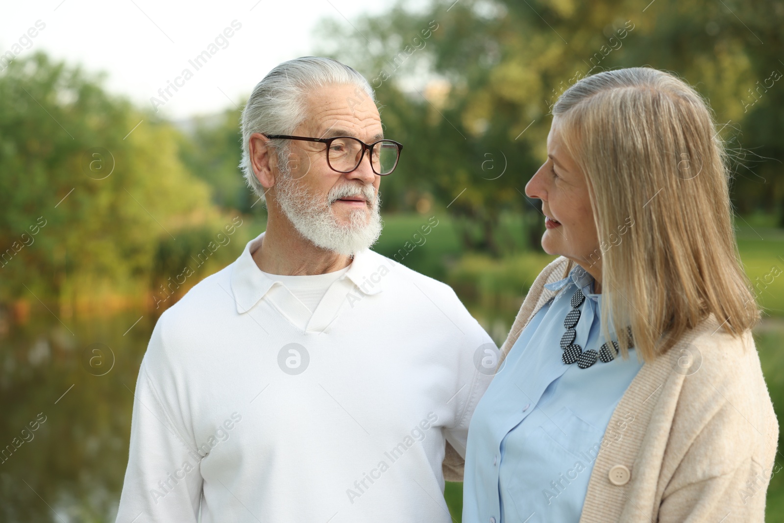 Lovely senior couple walking together near lake in park Photo of Lovely senior couple walking together near lake in park