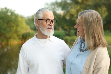 Photo of Lovely senior couple walking together near lake in park