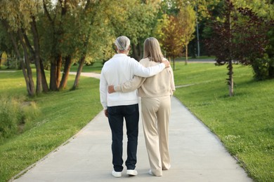 Photo of Lovely senior couple walking together in park, back view